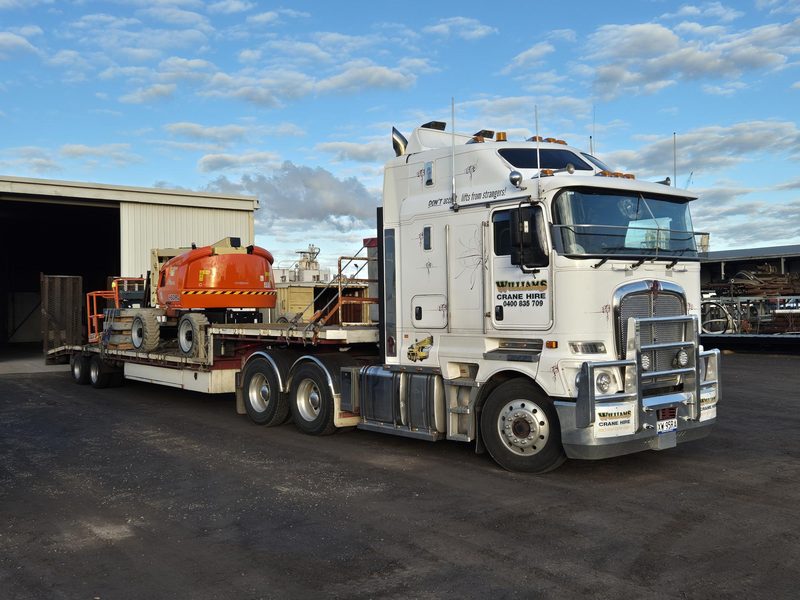 Kenworth K200 with low loader carrying a boom lift